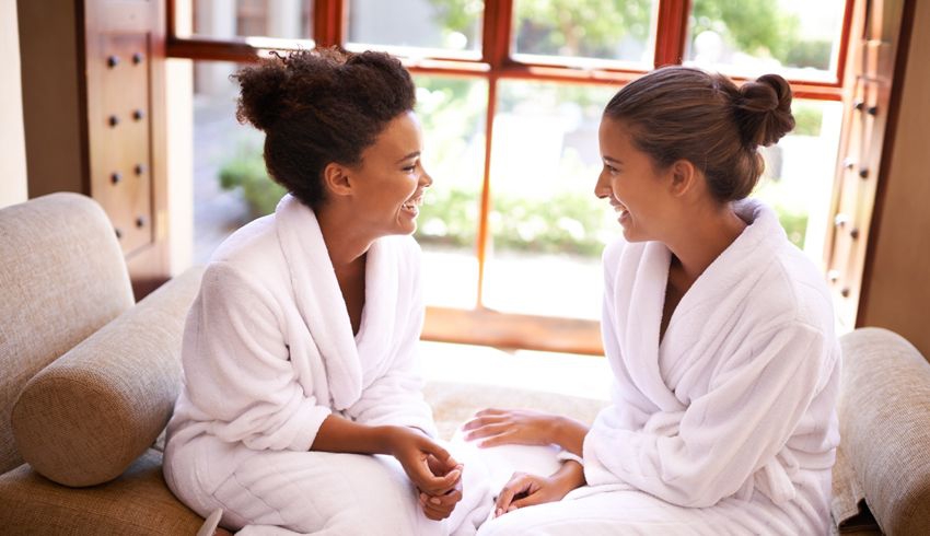 two women at the spa sit facing each other as they share a laugh